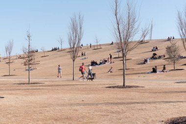 Oklahoma 'daki Scissortail Park' ta güneşli bir kış öğleden sonrasında eğlenen insanların fotoğrafı.
