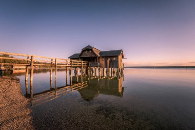 Almanya 'nın Bavyera şehrinde gün batımına karşı Ammersee Gölü üzerinde güzel bir kayıkhane manzarası