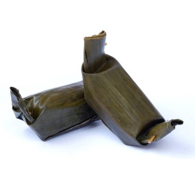 Muz yapraklarında buğulanmış, beyaz bir arka planda izole edilmiş yapışkan pirinç yakın plan çekimi.