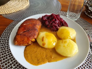 Ördekli patates ve beyaz tabakta kırmızı lahana.