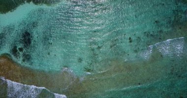 Temiz su ve sakin köpüklü dalgalarla güzel bir tropikal adanın hava aracı görüntüsü.