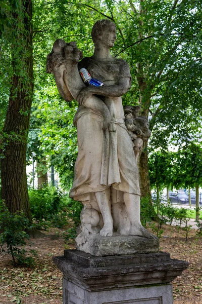 A vertical shot of an antique sculpture in a green park in Brussel, Belgium, Europe