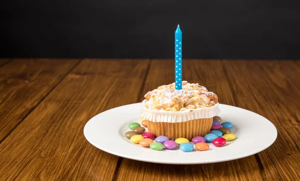 Talíř Muffinem Hořící Svíčkou Barevnými Bonbóny Dřevěném Stole Šedé Stěny — Stock fotografie