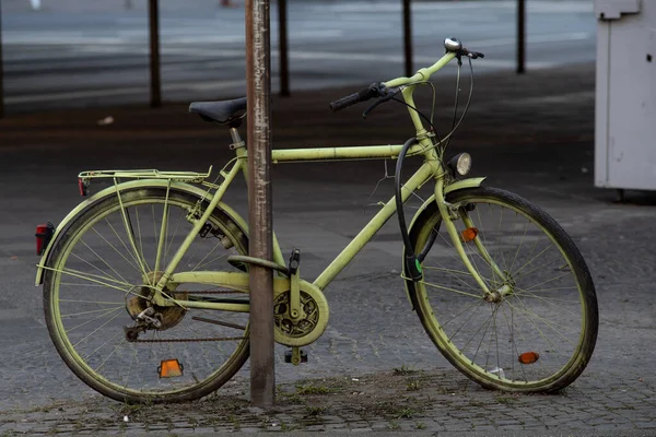 Uma Bicicleta Verde Amarrada Poste Metal Rua — Fotografia de Stock