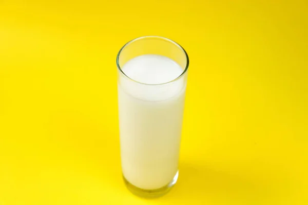 スタジオの黄色の背景に配置された新鮮な牛乳のガラス — ストック写真