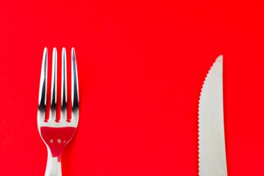 Gümüş çatal ve parlak kırmızı arka planda bir bıçak..