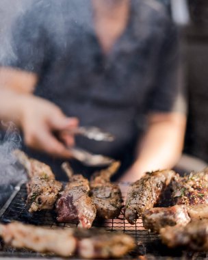 Izgaraya yakın çekim, yanan ateş, duman ve arka planda bir adam