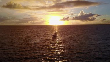 Yüzen bir tekneyle dramatik bir gün batımı.