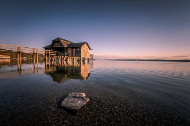 Almanya 'nın Bavyera şehrinde gün batımına karşı Ammersee Gölü üzerinde güzel bir kayıkhane manzarası