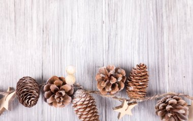 Üzerinde çam kozalakları olan ve fotokopi alanı olan bir Noel kurdelesinin üst görüntüsü.