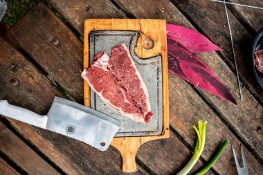 Kesme tahtasındaki bıçakla bir dilim çiğ biftek.
