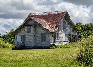 Fırtınalı bulutların altında paslı bir çatısı olan terk edilmiş eski bir eve yakın çekim.