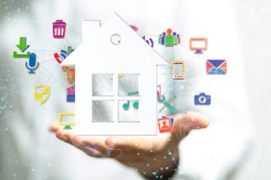 Bir adamın avucunda çeşitli kablosuz bilgisayar ve ev aletleri olan bir evin hologramı. IOT konsepti