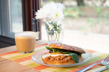 Masada kahve ve çiçeklerle nefis bir hamburger.