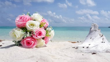 Güneşli bir yaz gününde kumsalda bir buket gülün yakın çekimi.