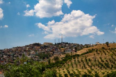 Bulutlu bir gökyüzünün altındaki binalar, evler ve ağaçlarla Irbid şehri.