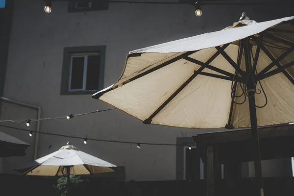 屋外のカフェで太陽の影の傘のローアングルショット ストリングライトガーランド — ストック写真