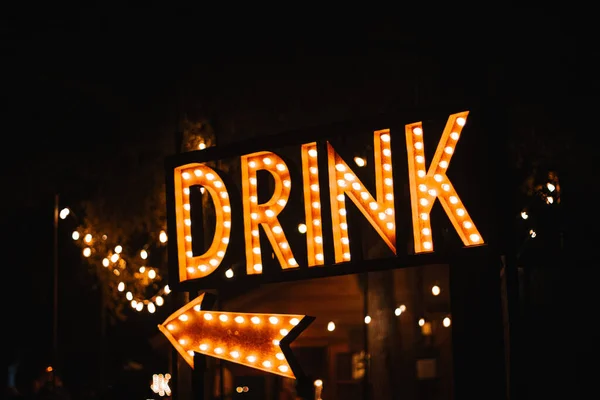 夜のデカンソ ガーデンズの矢印が付いた大きなライトサイン Drink — ストック写真