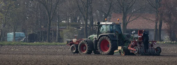 Hollanda, Nederweert 'te bakım işi yapan bir adamla tarlayı süren bir Fendt traktörü.