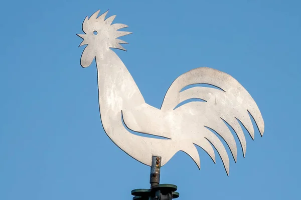 A closeup of a Rooster shaped metal weather vane against clear blue sky