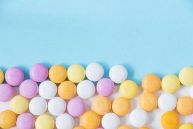 İki renkli arkaplandaki düğme şekilli şekerlemelere yakın çekim.