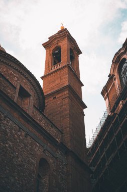 Floransa 'daki Capella Tıp Kulesi' nin dikey alçak açılı görüntüsü. Tepesinde fırtına bulutları var.