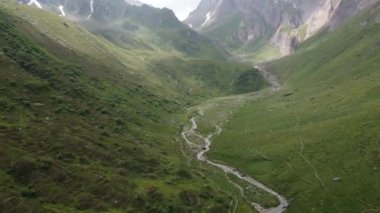 Ortasında küçük bir su yolu olan güzel yeşil dağların havadan çekilmiş görüntüsü.