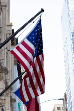 Amerika Birleşik Devletleri bayrağının açık gökyüzü olan bir binadan sallanışını yakından çekiyoruz.