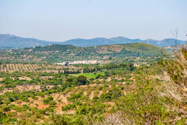 Capdepera, Majorca 'da dağlarla çevrili ağaçlarla ve binalarla dolu yeşil manzaranın büyüleyici bir görüntüsü.