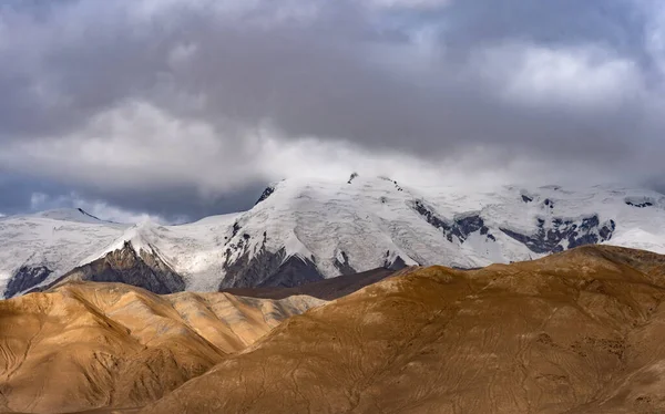 Piękny Krajobraz Piaszczystych Wzgórz Śnieżnych Gór Pod Zachmurzonym Szarym Niebem — Zdjęcie stockowe