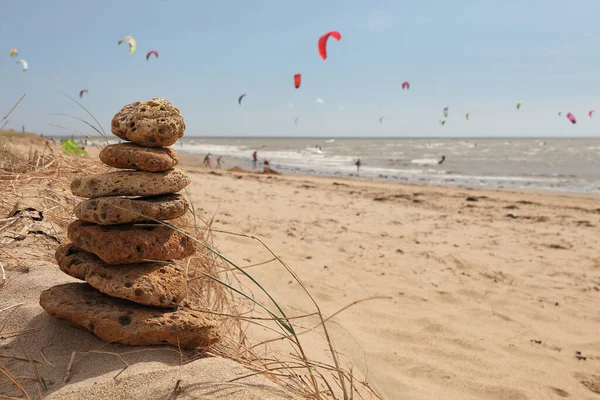 Tiro Foco Seletivo Pedras Empilhadas Uma Praia Areia Com Kitesurfers — Fotografia de Stock