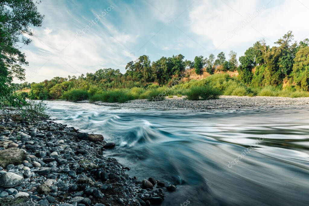 A long exposure of the Trancura River with trees in the background in La Araucania, Chile