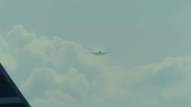 Başka bir uçağın penceresinden görünen bulutların üzerinde uçan bir uçak.