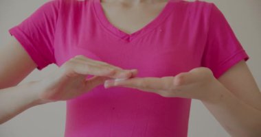 Pembe gömlekli bir kadın beyaz arka planda izole edilmiş el nemlendiricisi sürüyor.