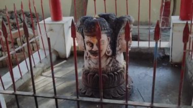 Hindistan 'da bir tapınakta çitin arkasında dört yüzlü bir heykel.