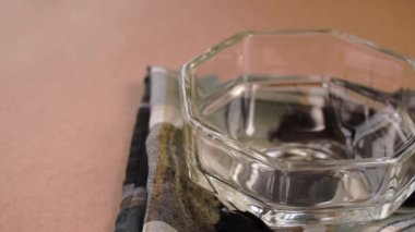 Kahve çekirdekleri yakın plan çekimde pembe arka planda cam bir kaseye düşüyor.