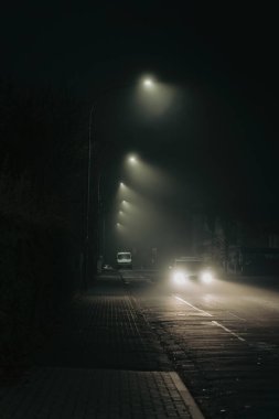 Gece geç saatlerde sokakta çekilmiş dikey bir araba görüntüsü.