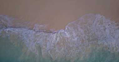 Kumlu bir sahilde köpüklü yumuşak okyanus dalgalarının hava manzarası.