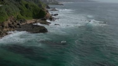 Kayalık sahile vuran köpük dalgalarının hava görüntüsü.