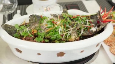 Lokantada servis edilen beyaz tabakta servis edilen bir buharlı balık görüntüsü.