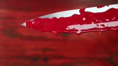 Kırmızı arka planda bıçak üstüne kan damlaları, gizem ve korku