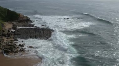 Kayalık sahile vuran köpük dalgalarının hava görüntüsü.