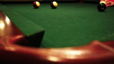 Bir erkeğin bilardo topunu deliğe attığı yakın çekim görüntüleri.
