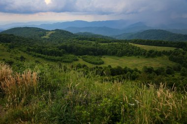 Ormanla kaplı, arka planda bulutlu bir gökyüzü olan dağ sırasının güzel bir üst manzarası.