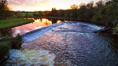 A glowing sunset reflection in the weir on the River Boyne at Ardmulchan, County Meath, Ireland clipart