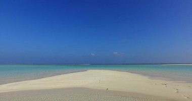 Asya 'da açık mavi gökyüzünün altında okyanusla çevrili kumlu bir sahil.