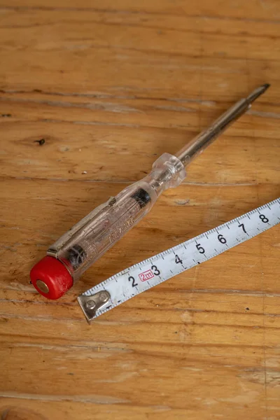 木製のテーブルの上に古い電圧電気試験機と白の測定テープの垂直ショット — ストック写真