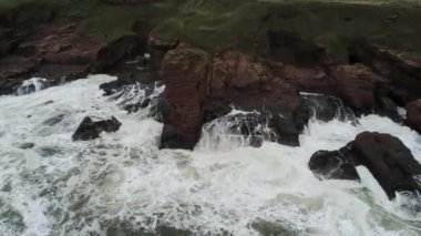 Dalgaların yavaşça Arbroath uçurumlarını yıkaması ve su sıçratması.