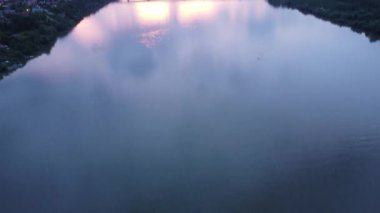 Şehir mimarisi ve ormanlarından akan bir nehrin hava manzarası muhteşem günbatımı gökyüzünü yansıtıyor.