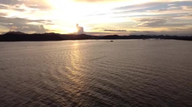 Akşam karanlığında dağ siluetleriyle sakin bir gölün üzerinden geçen bir pan drone.